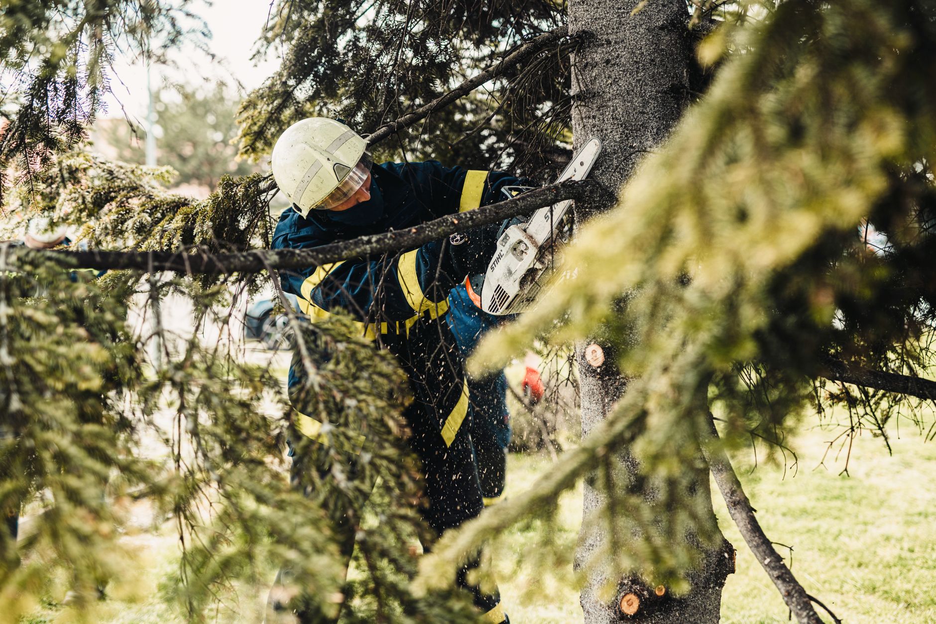 Firefighter in protective gear using chainsaw to cut tree branches outdoors in Longview, TX
